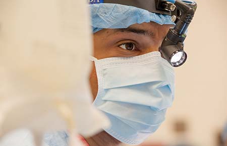 A close-up of a physician in scrubs about to perform surgery.