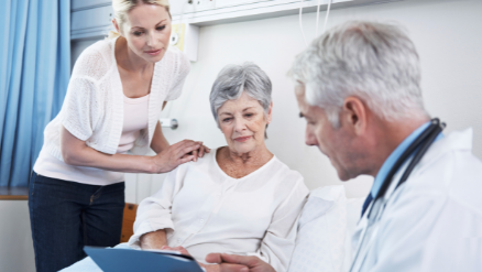 A physician looking at a tablet with an elderly patient and a young woman.