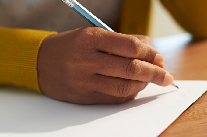 A person's hand writing on a piece of paper