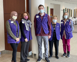 A group of people wearing masks and looking at the camera in their volunteer uniforms.