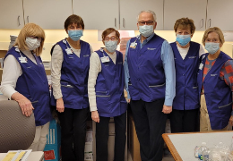 A group of people wearing their purple volunteer vests and masks.