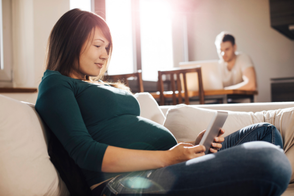 pregnant woman on couch, looking at phone
