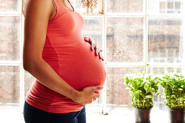 Pregnant woman holding her stomach in a downtown apartment