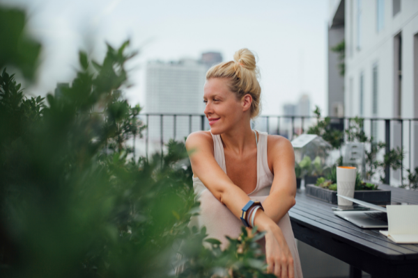 Woman sitting on deck outside her apartment