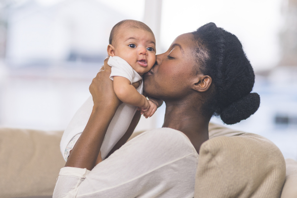 Woman kissing newborn baby
