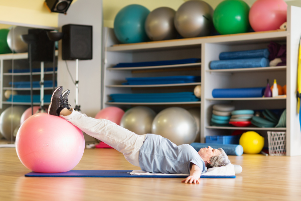 Elderly woman using exercise equipment during physical therapy