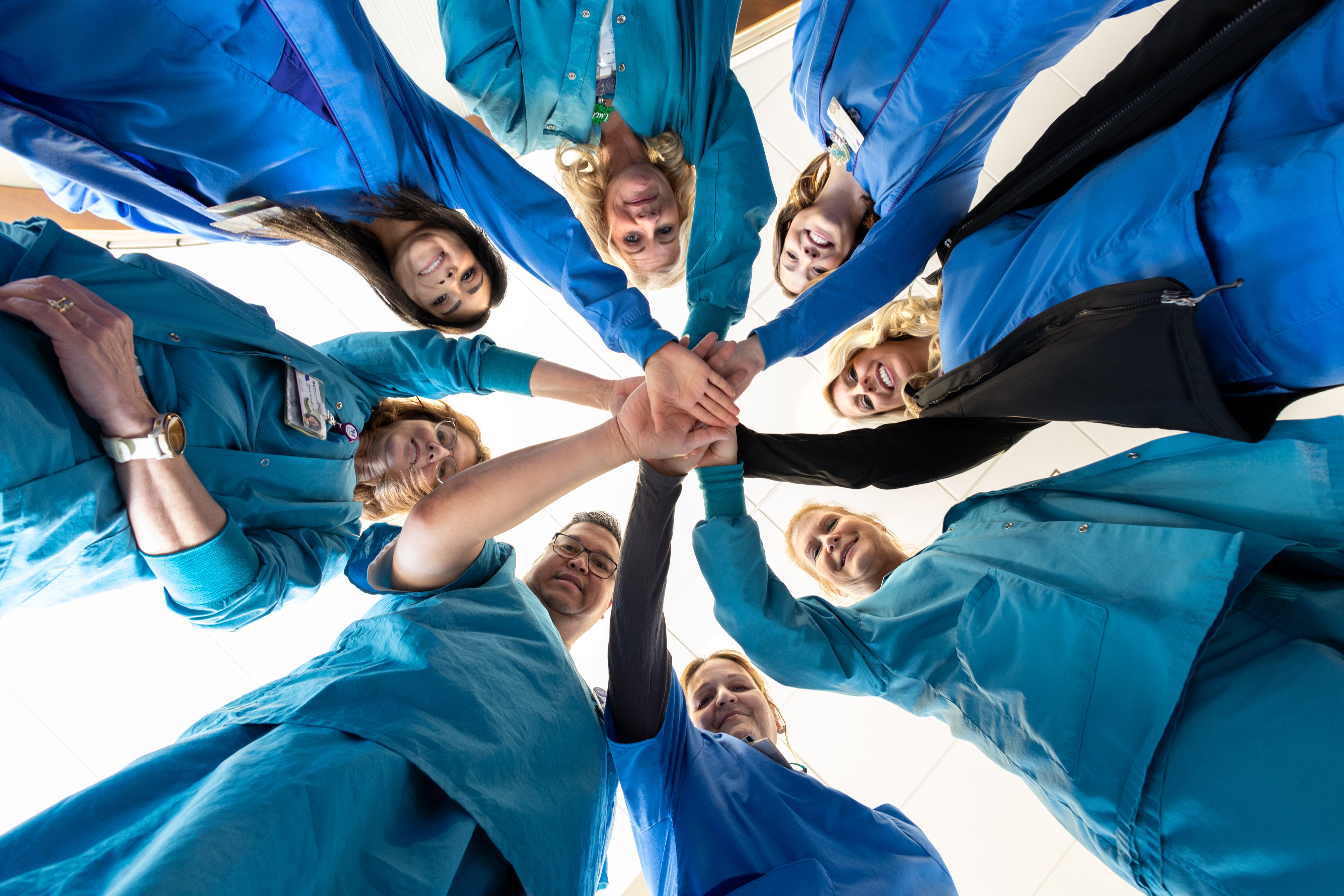 care team in a circle with hands in