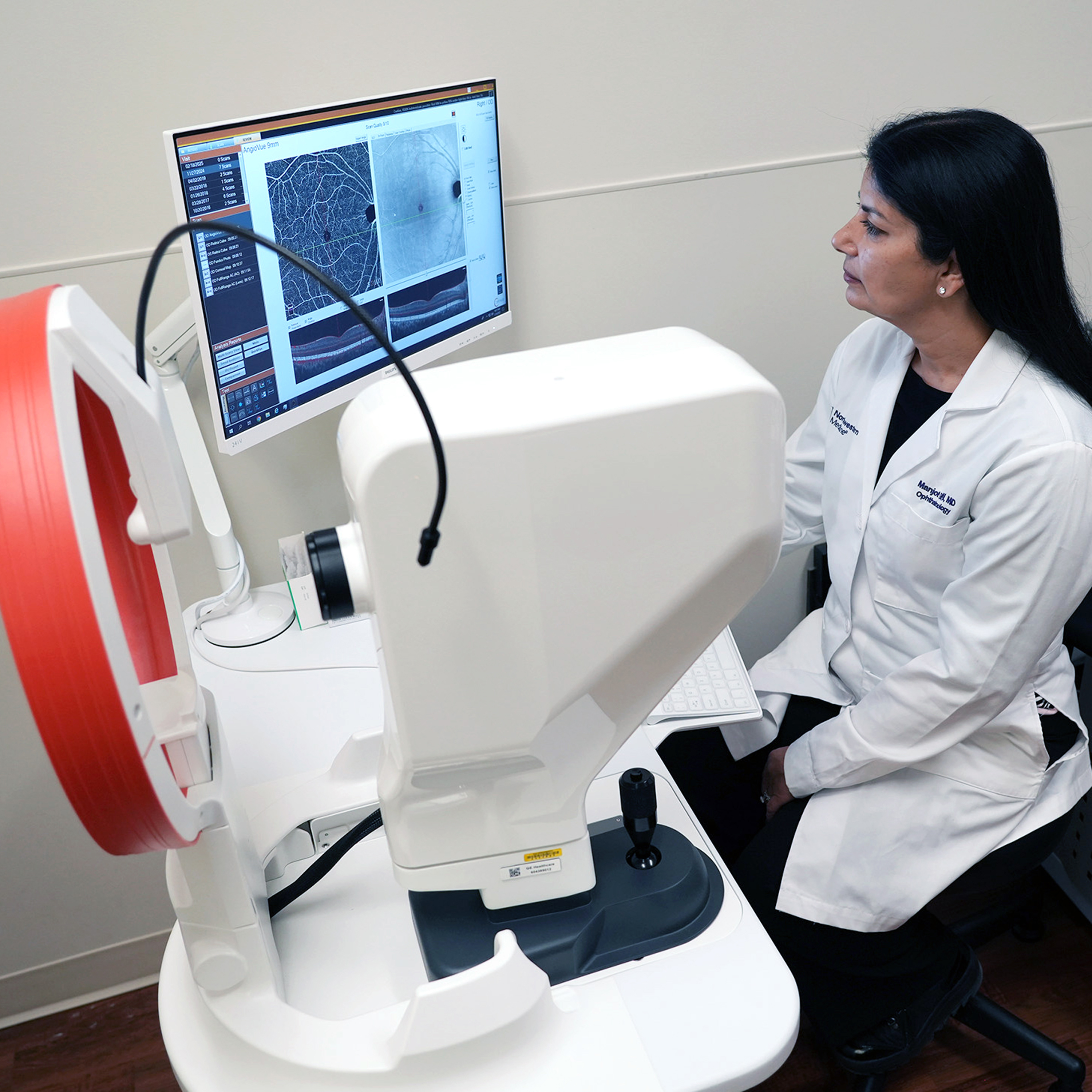 Ophthalmologist Dr. Gill reviewing retinal imaging scans on a diagnostic monitor during an eye examination.