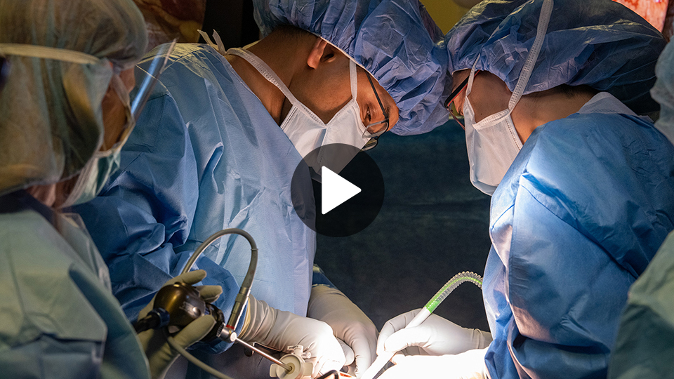 Two physicians in blue lab coats performing an operation.