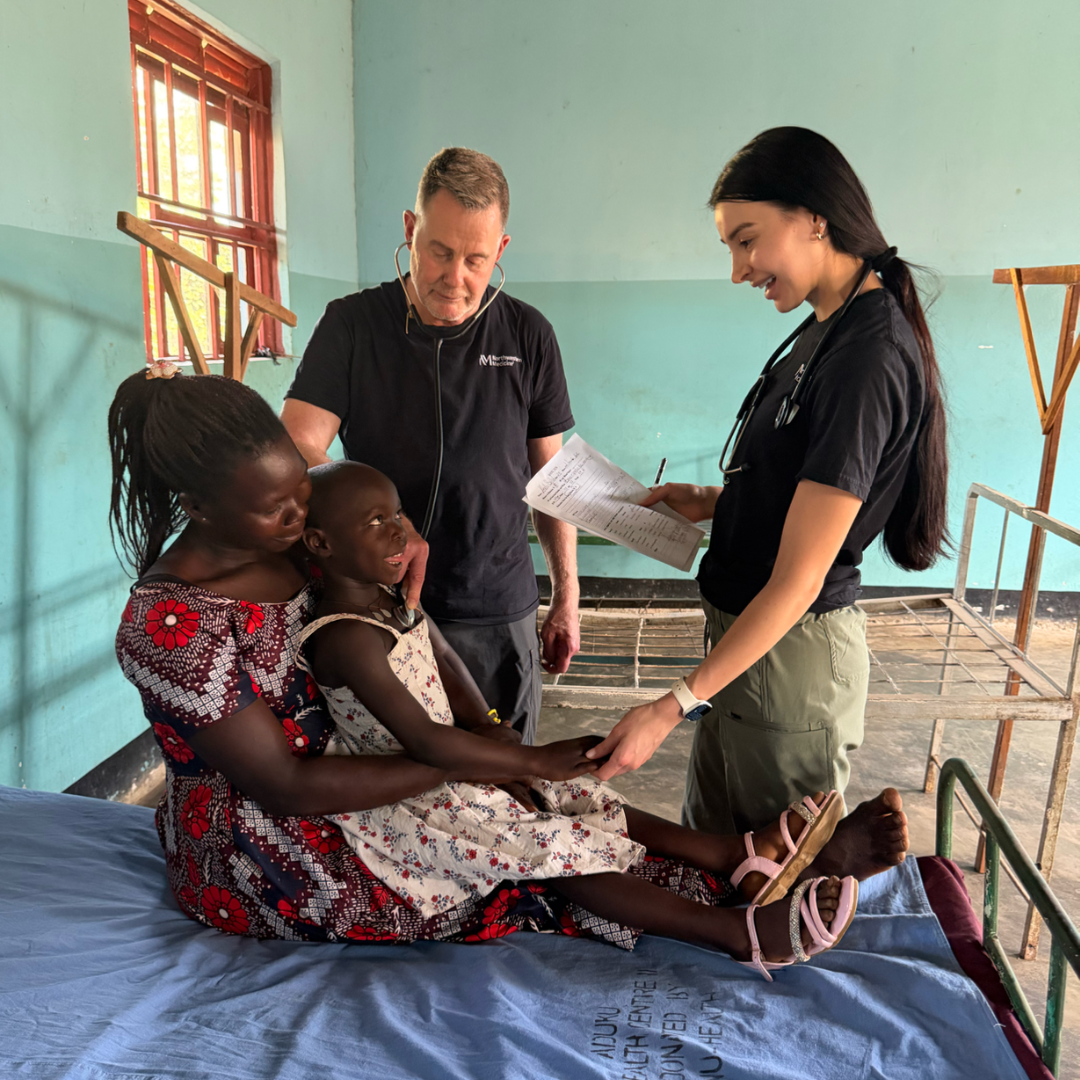 Healthcare professionals consult with a patient and child in a clinical setting.