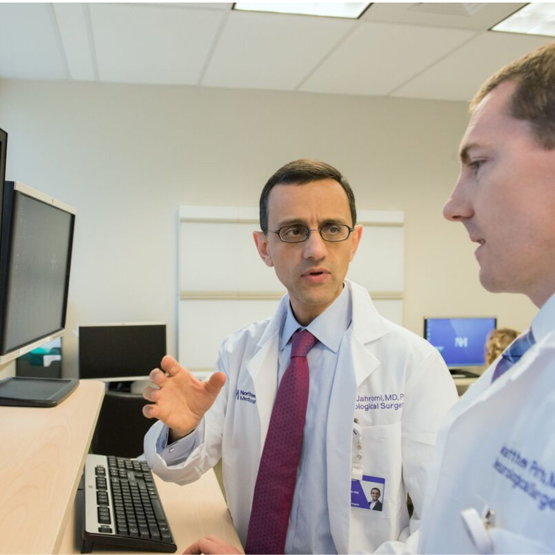 Two physicians review medical imaging at a computer workstation.
