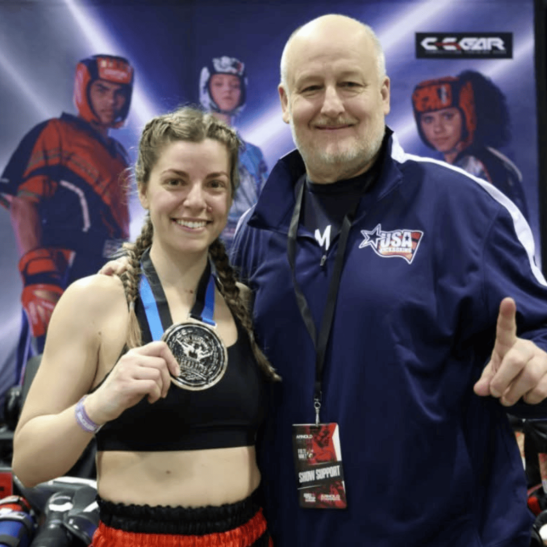 Athletic trainer and athlete holding a medal posing for a photo.