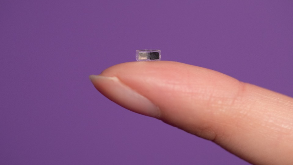Fingertip holding a small pacemaker.