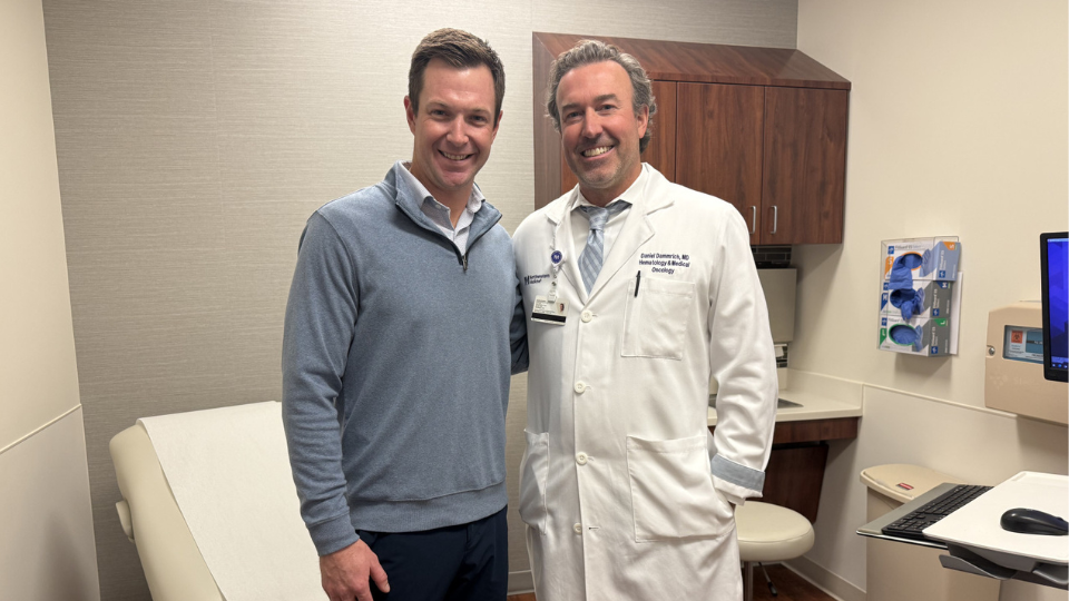 Patient and doctor posing for a photo in a hospital room.