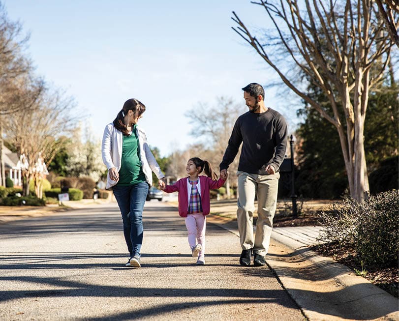 Family of three walking in suburban neighborhood