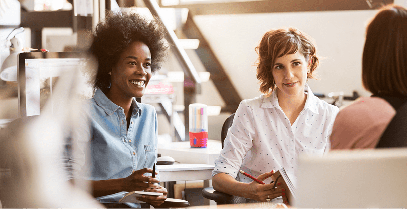 Happy businesswomen discussing with female colleague in office