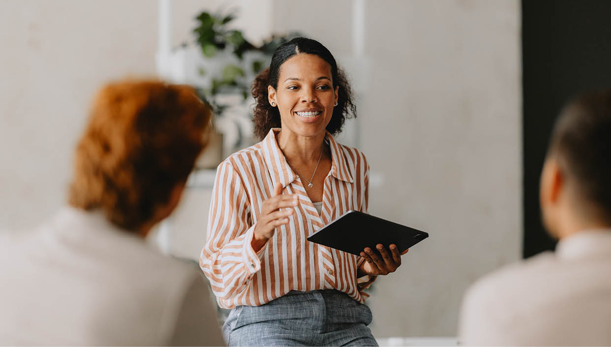 Confident businesswoman leading a group business meeting at a bright beige office. Professional interaction and teamwork concept.