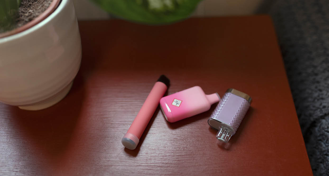 Close-up of electronic cigarettes on table beside flower pot