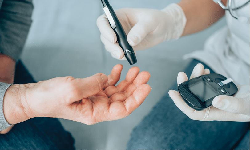 Unrecognizable female doctor doing glucose blood test on her senior patient during a home visit.