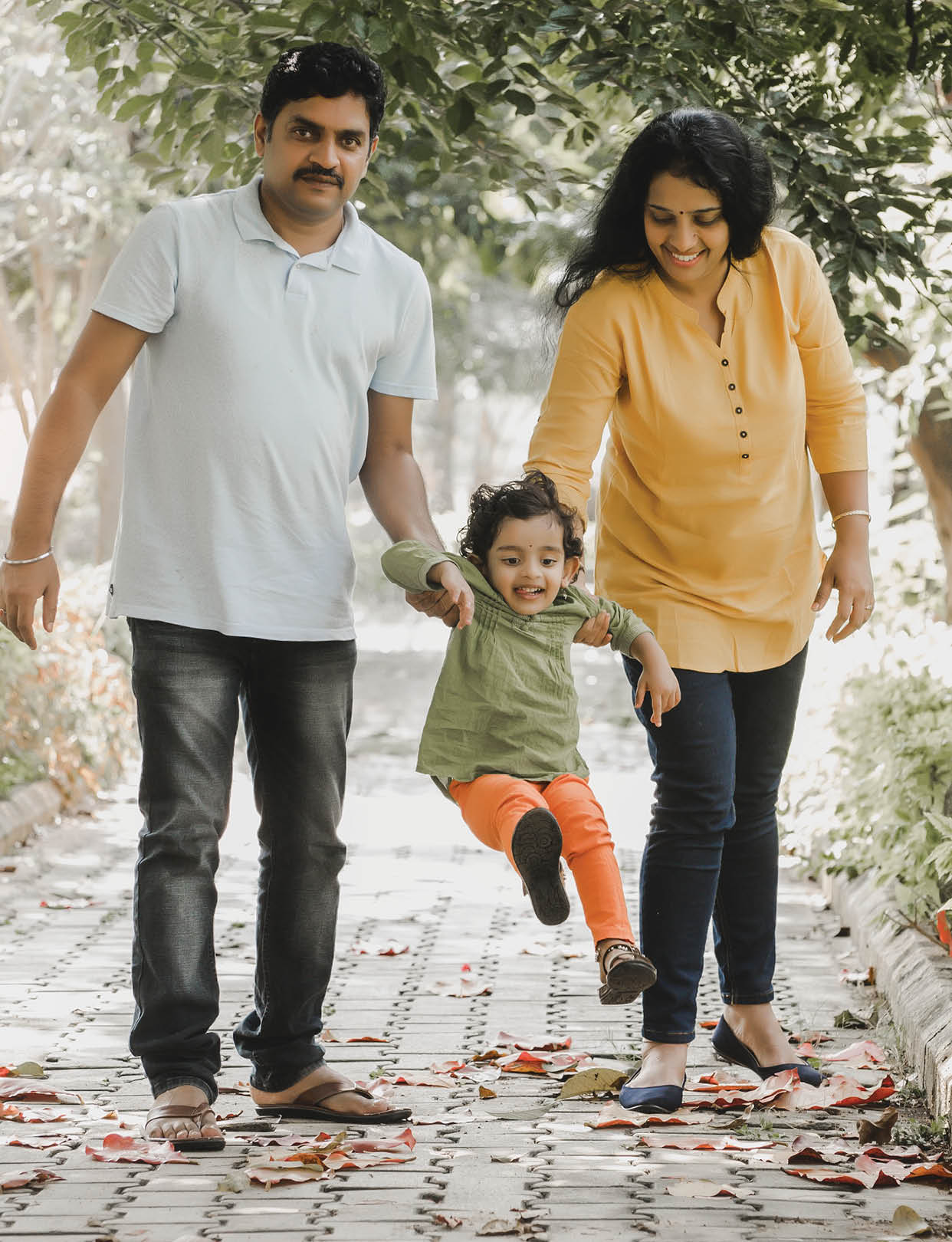 Indian parents playing with their young daughter in a park