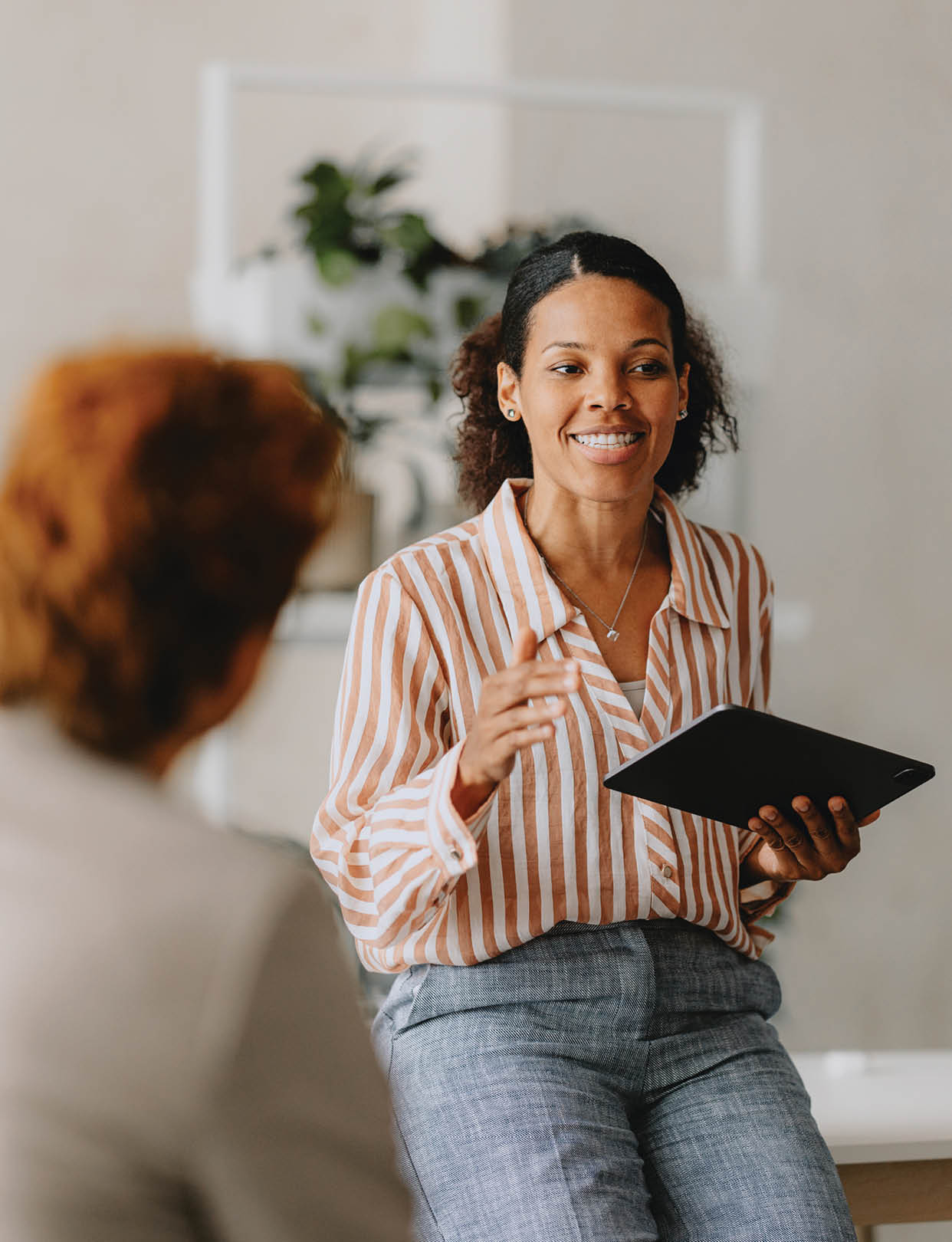 Confident businesswoman leading a group business meeting at a bright beige office. Professional interaction and teamwork concept.