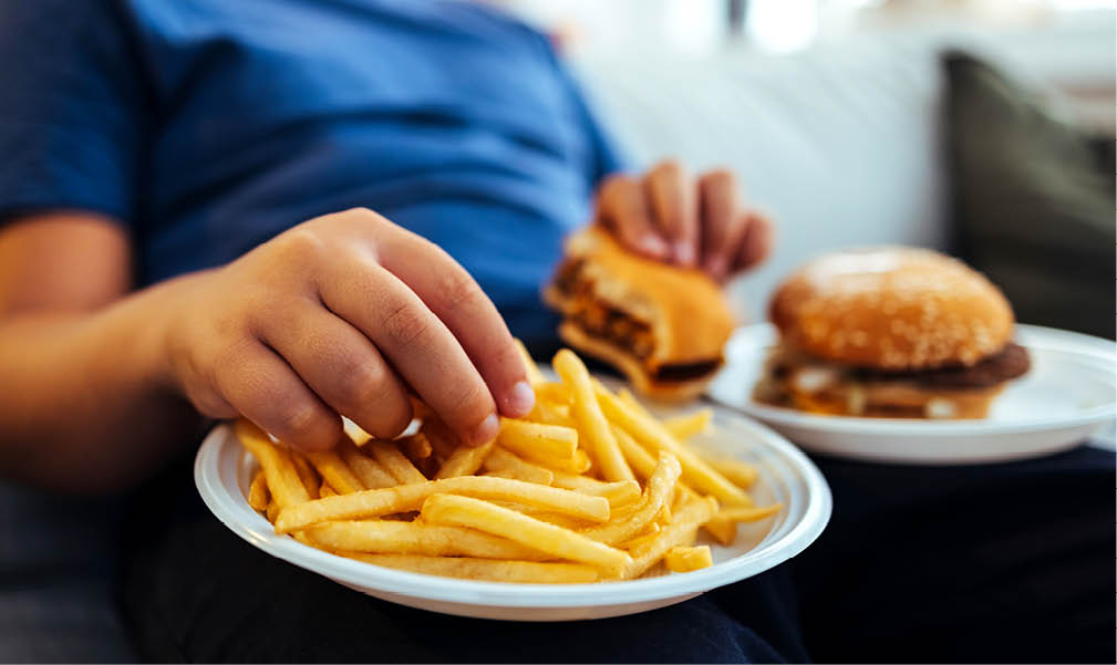 Overweight teenage boy eating too much fried food