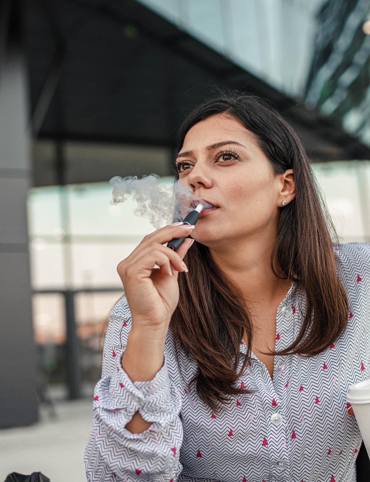 Beautiful businesswoman taking a coffee and cigarette break from the office