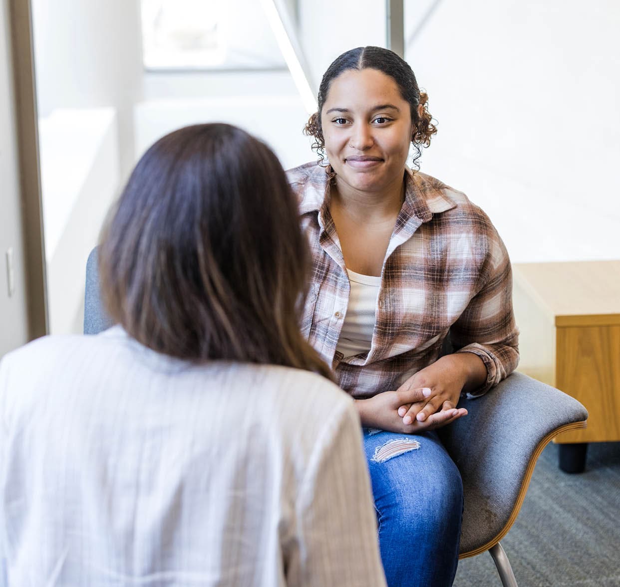 The young adult female student meets with her college counselor to talk about her classes.