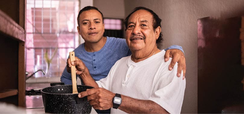 Portrait of a latin father and son cooking at home