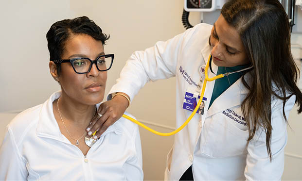 A woman wearing glasses has her blood pressure taken by a nurse. Description generated by AI
