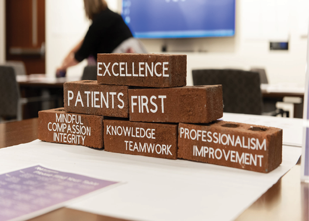 A brick wall with the words “Excellence, Patients First" written on it. Description generated by AI