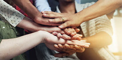 A group of people with their hands together. Description generated by AI