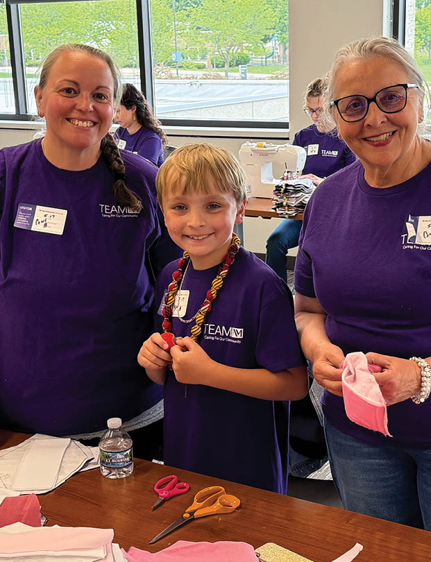 Three women and a boy are making paper cranes. Description generated by AI