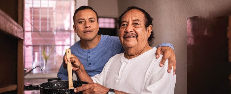 Portrait of a latin father and son cooking at home