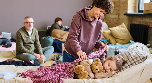 A woman is holding a teddy bear while a child sleeps. Description generated by AI