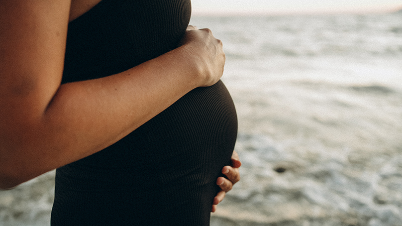 Pregnant person on the beach.