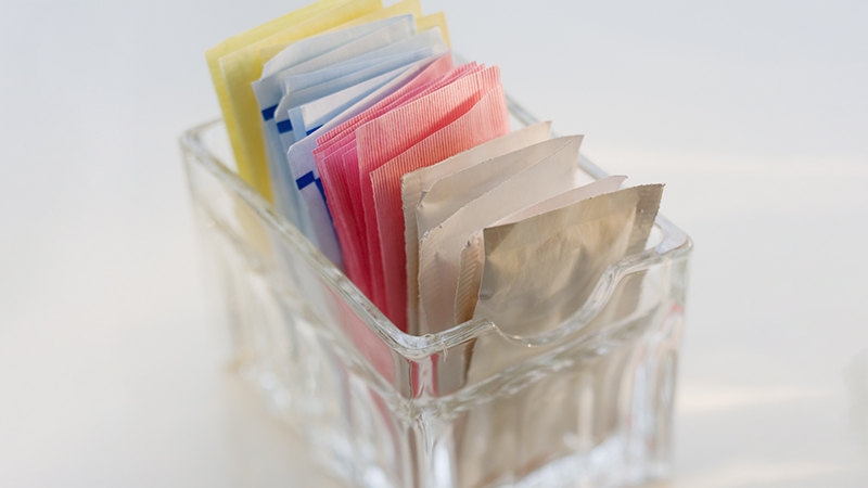 A close-up of sugar and artificial sweetener packets.