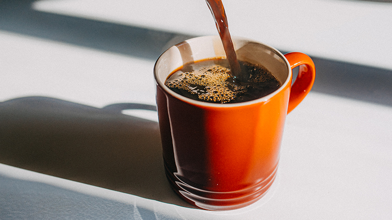 Coffee pouring into a red mug on a white table