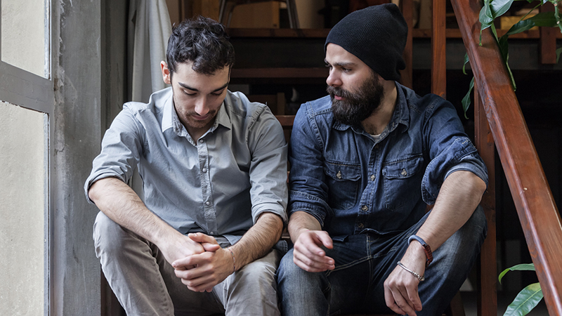 Two people sit on a staircase having a serious conversation. 