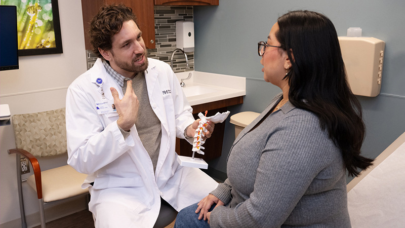 Healthcare professional consulting with patient in medical office, discussing treatment plan and answering questions in a friendly manner.