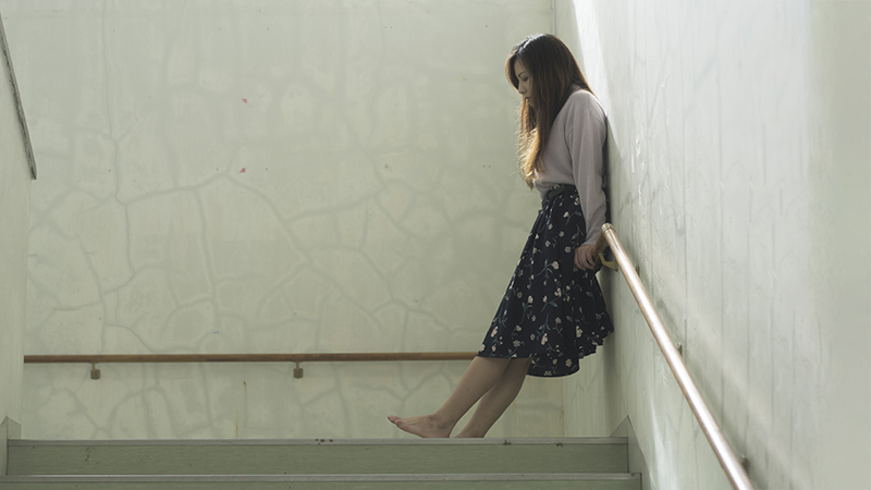 Winded person waiting on a stair landing.