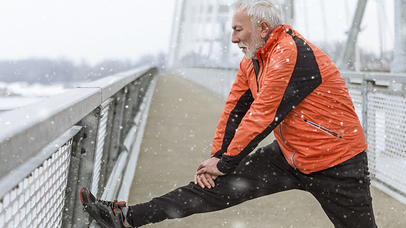 person with one leg stretched out with snow falling