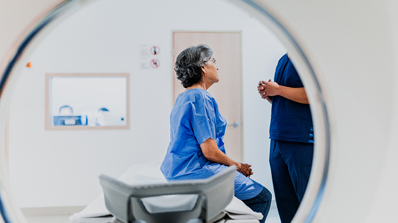 Patient talking to a clinician while seated on an MRI machine.