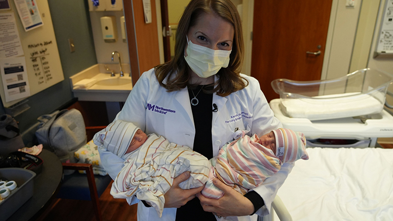 Doctor in a mask and white coat holds two twin infants