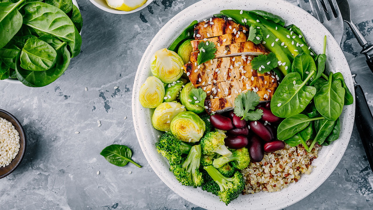 bowl of grilled chicken breast, bright green veggies and quinoa