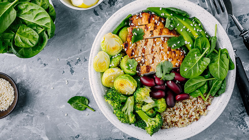 bowl of grilled chicken breast, bright green veggies and quinoa
